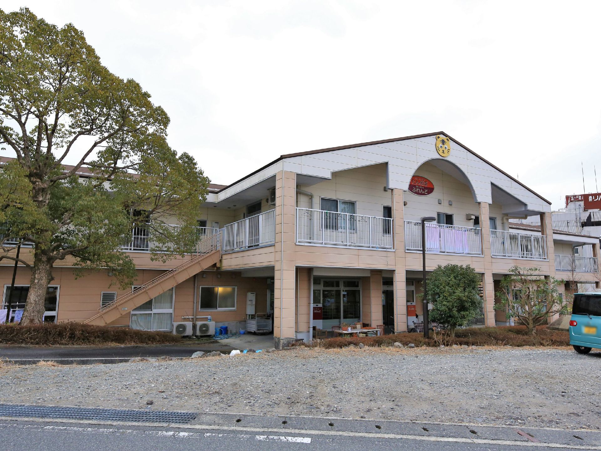 2階建ての商業施設のような造りの外観。2階部分は屋根付きのベランダが巡らせてあり、アーチの上にはコミカルな動物のロゴがついている。