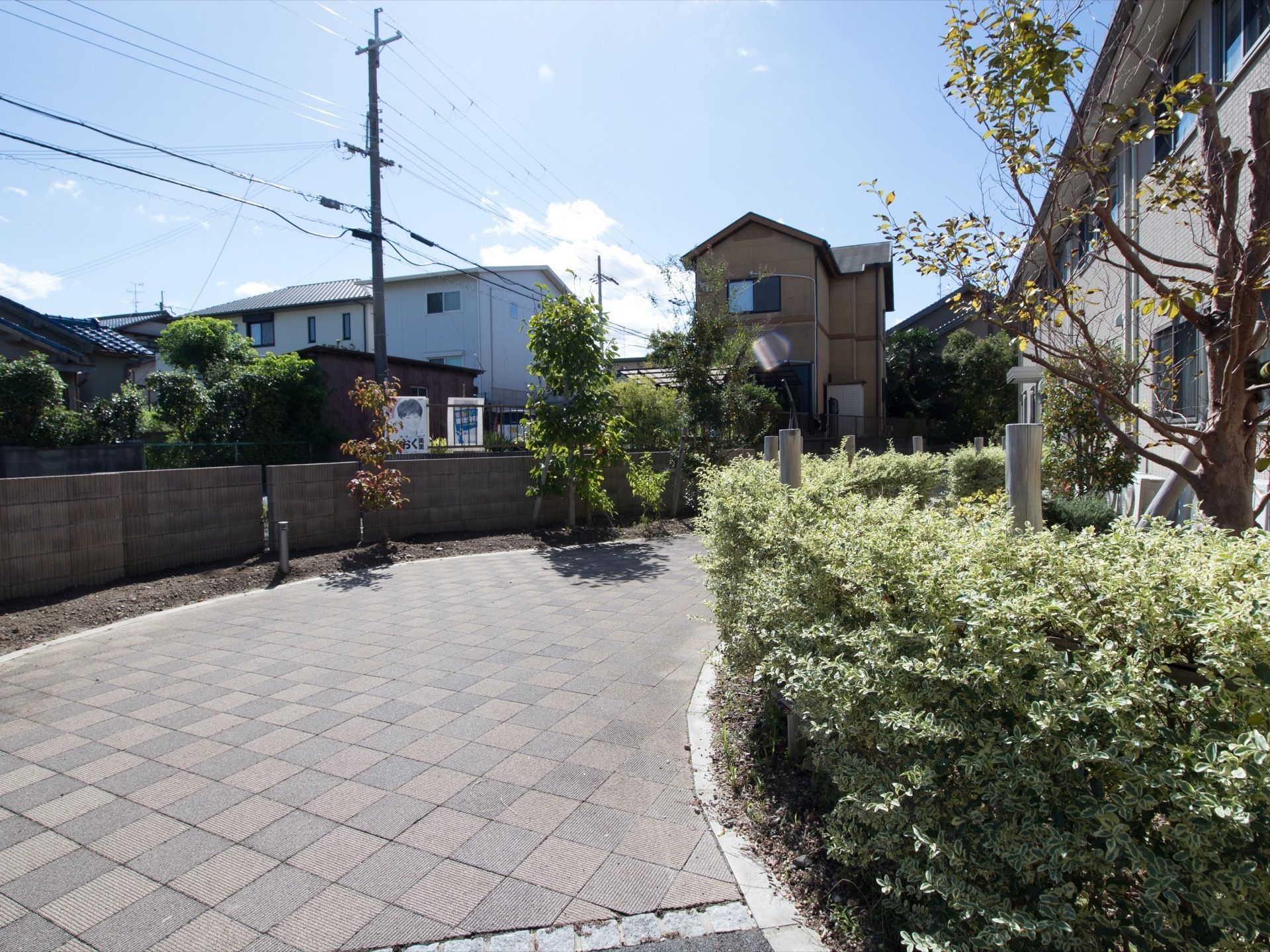 施設をぐるりと囲んだ散歩道がある。両脇は生垣とフェンスに囲まれている。周囲は住宅地が広がり、空がとても広い。