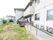 ２階建ての建物である。１階にはウッドデッキが設置されており、物干し竿には洗濯物が干されている。庭には畑が設けられている。
