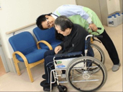 車いすに座っている男性入居者に、横から話しかける男性スタッフ