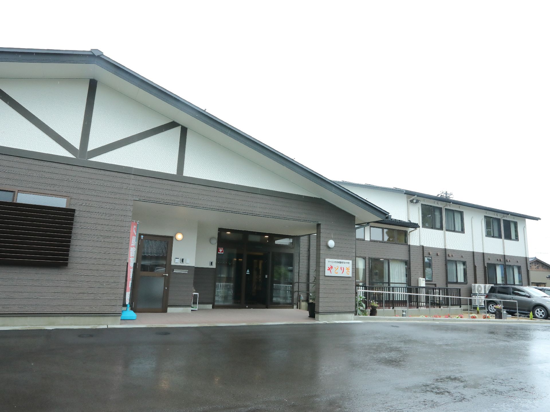 建物があり、2階建てになっている。建物の1階部分の外壁は灰色になっており、2階部分は白色に塗られている。