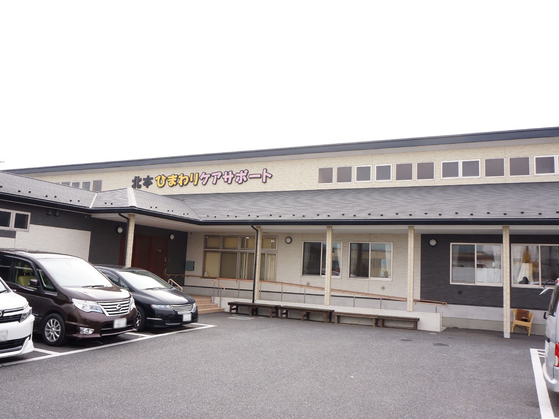 施設の建物はツートンカラーの外観で、大きな看板を設置している。また敷地内には広々とした駐車スペースが用意されている。
