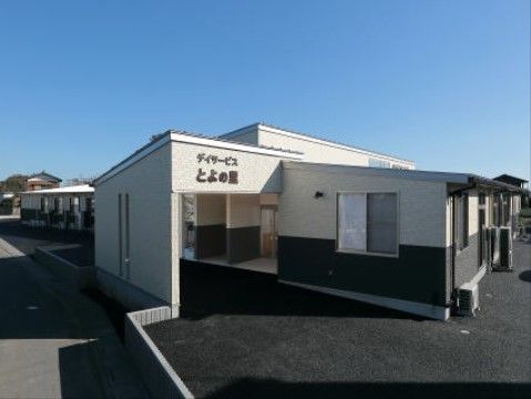 周辺が黒いコンクリートで囲まれている、白色と黒色の外壁をした施設外観