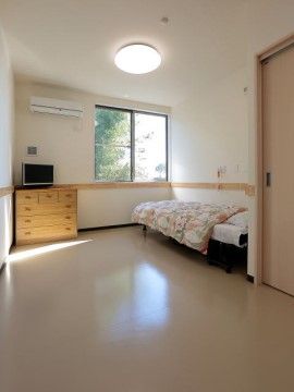 白で統一された清潔感のある居室である。大きな窓からは陽が射し込み、自然豊かな木々を眺めることができる。