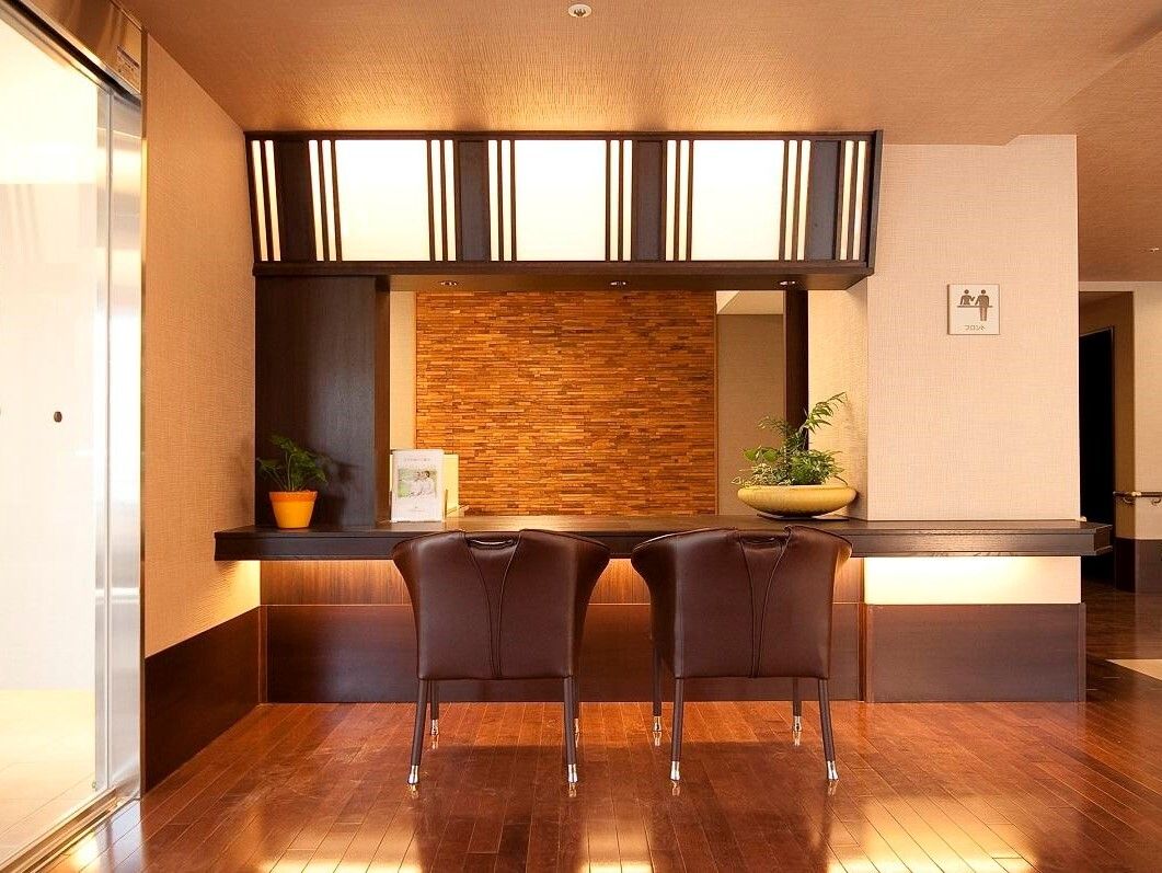 革張りの椅子が２脚セットされた、ホテルを思わせる木調のフロント