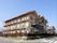クリーム色の３階建ての三角屋根の建物である。建物の周りに低めの樹木を植えている。外側に階段を設置している。