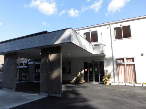 玄関前に広く屋根が設置されている、白い外壁の施設外観