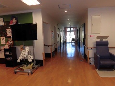 廊下の途中に設けられた広いスペースには、テレビや椅子、胡蝶蘭の鉢植えが置かれている。壁に取り付けられた掲示板には、絵や詩が飾られている。
