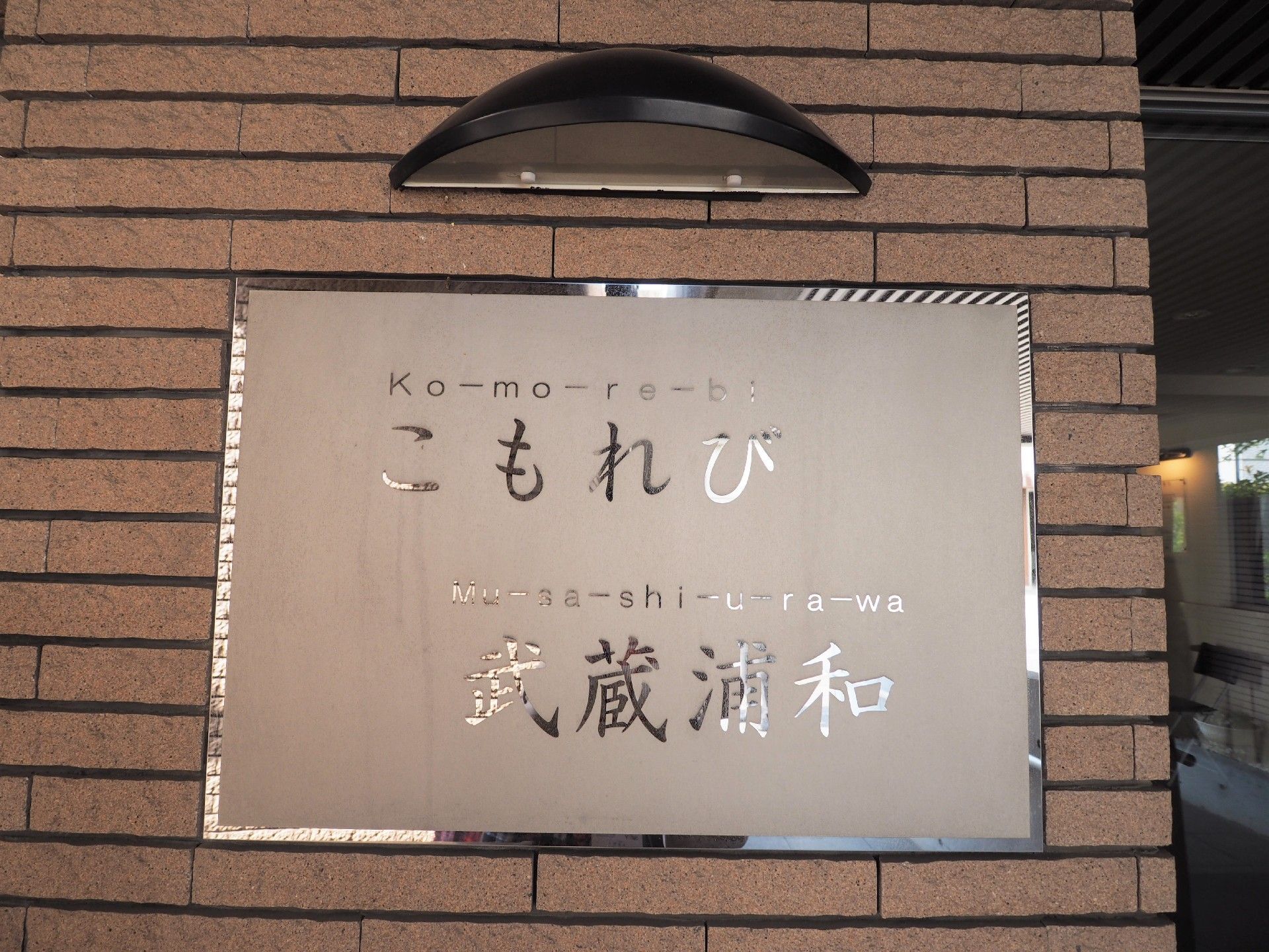 レンガ風の壁に設置されている、上部にライトが取り付けられた施設の看板