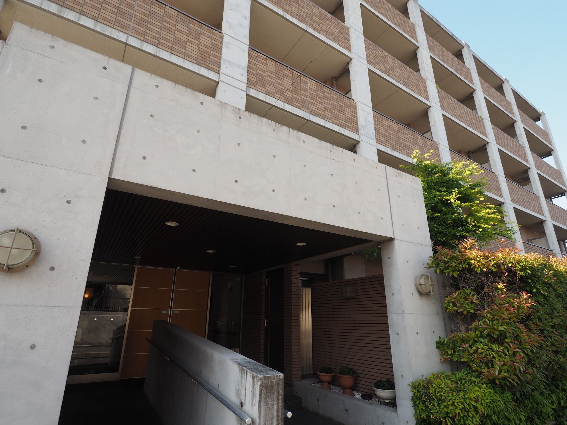 右手に階段、左手にスロープがあり、その中央に手すり付きのコンクリ低壁が設置されている玄関