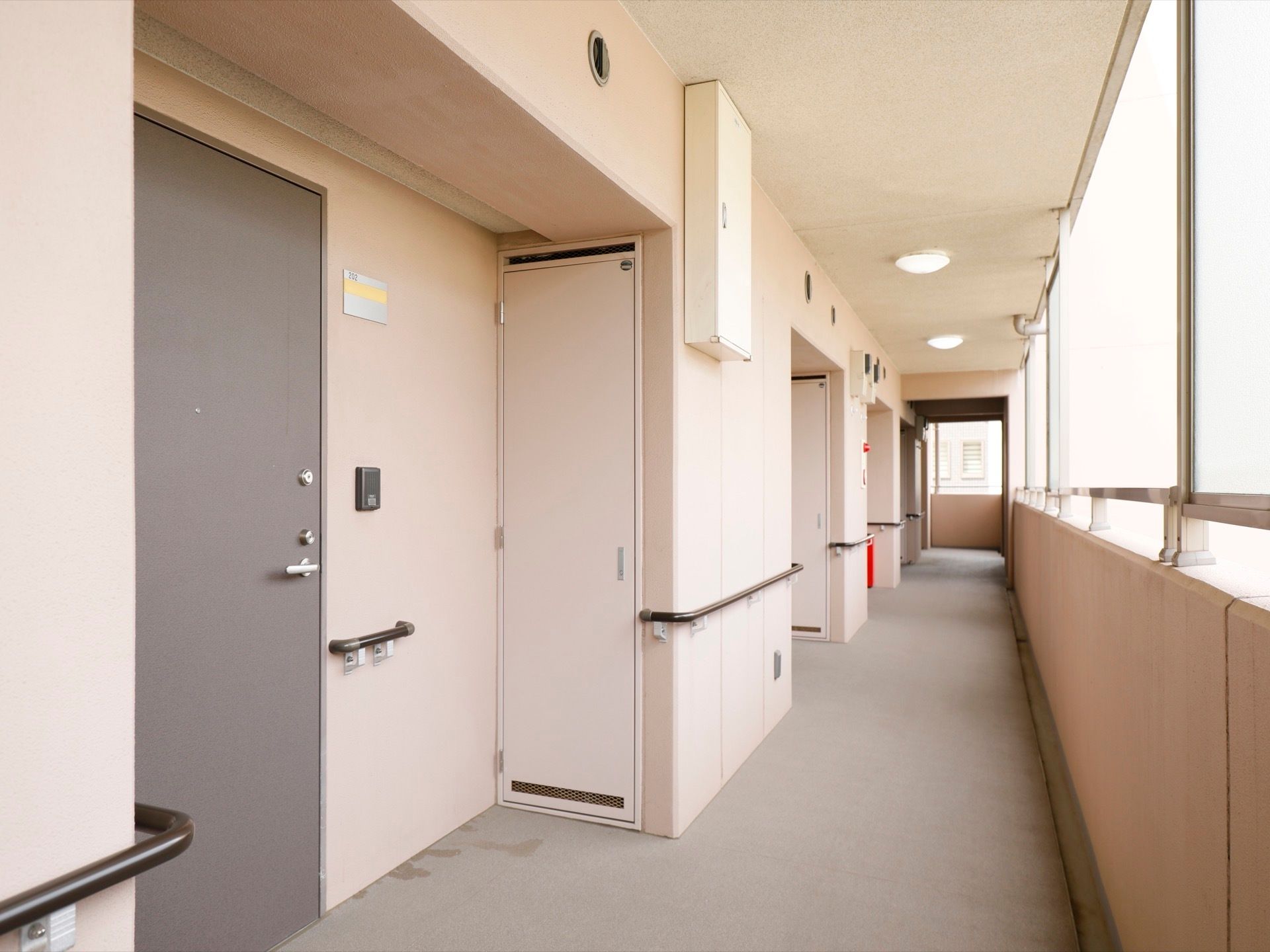 通路は通常のマンションのような雰囲気の外廊下となっている。片側にはすりガラスが設置されており、柔らかい日差しが入ってきている。