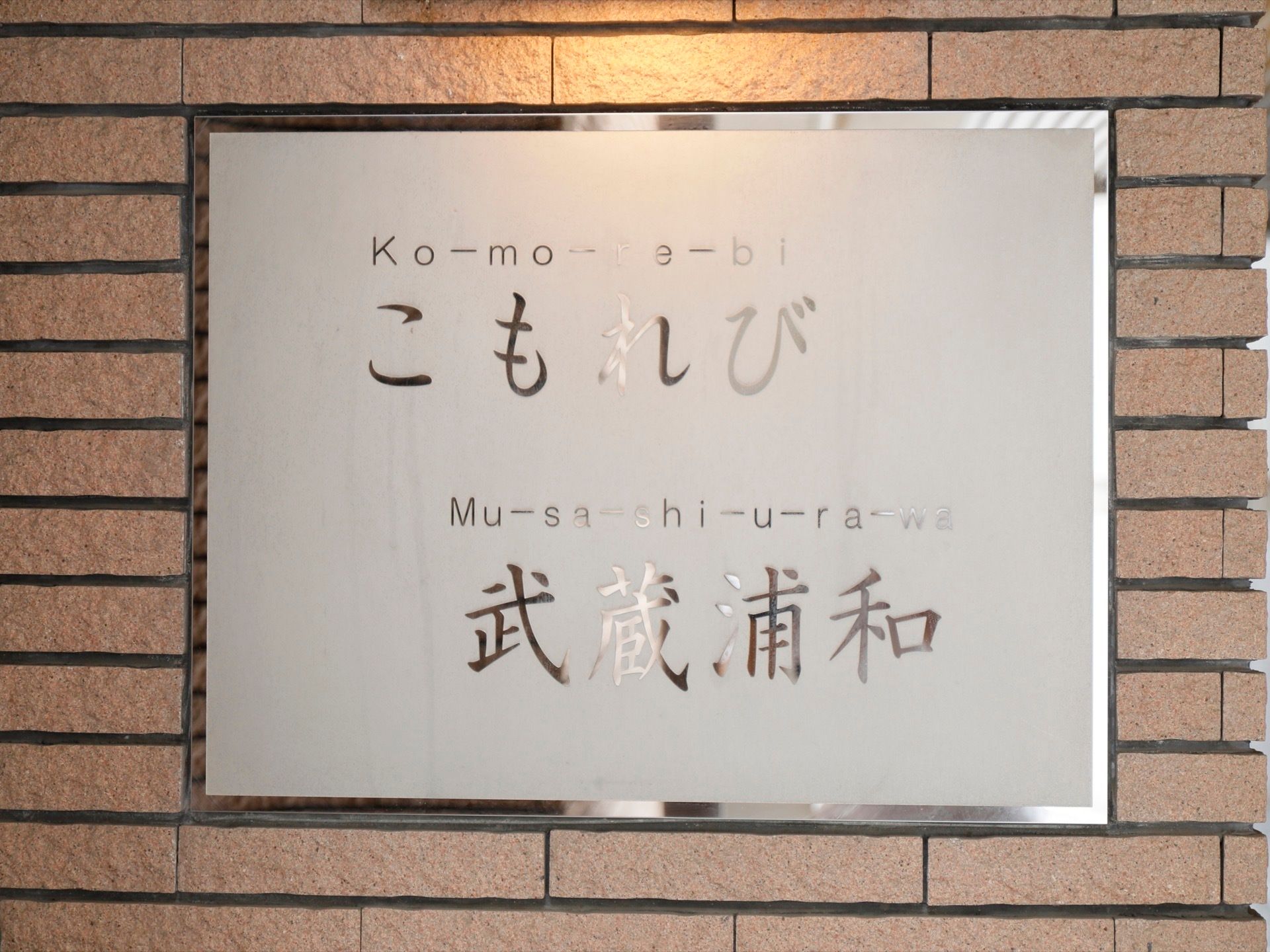 施設名が書かれたシルバーの看板が取り付けられている。ブラウン系の外壁とよくマッチしていて、一般のマンションのような雰囲気である。