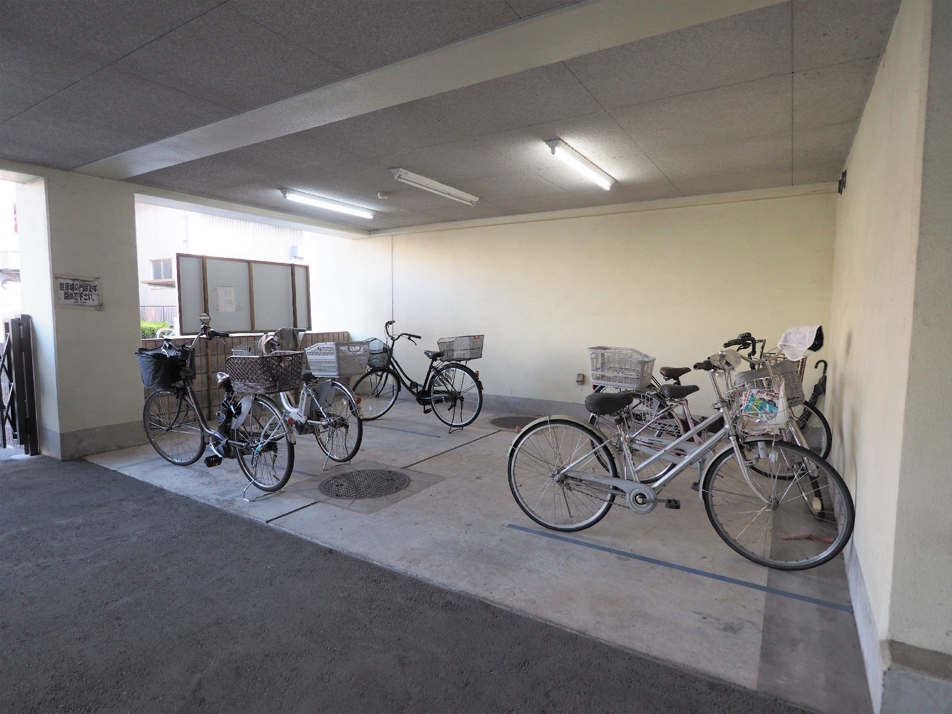 天井に蛍光灯が三か所設置されているコンクリート造りの自転車置き場