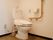 共用設備として用意されているトイレの様子。床はカーペット素材になっており、壁には手すりとナースコールがある。