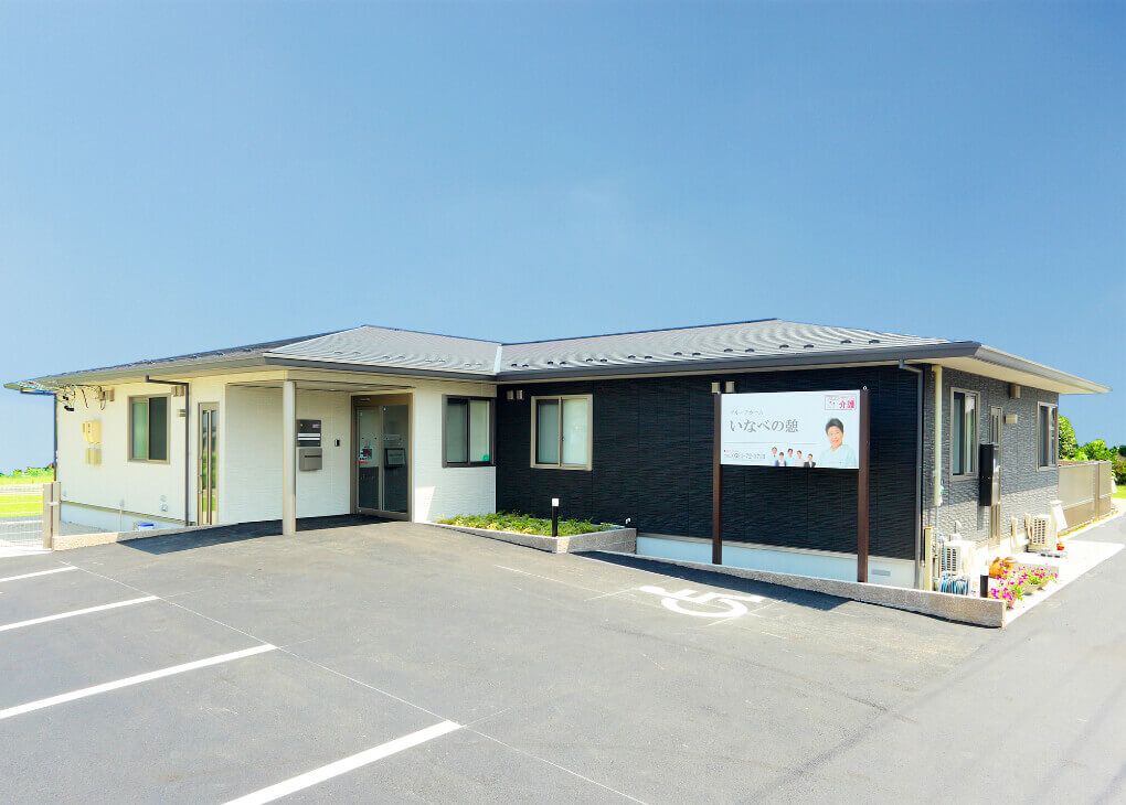 鉄骨平屋建ての施設である。建物前には、広い駐車場が設けられており、送迎車が駐車されている。エントランスには、ひさしが付いている。