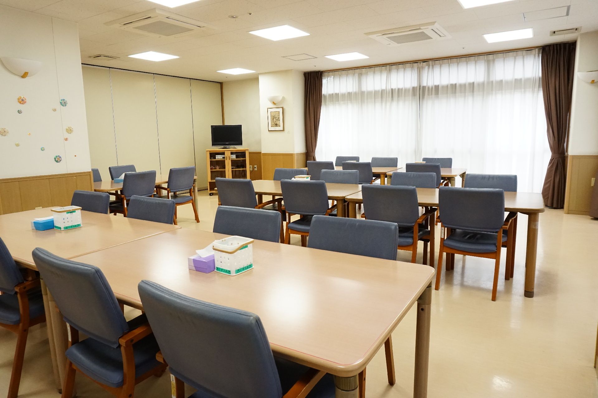 正方形のテーブルに、青色の背もたれ椅子が設置されているリビング