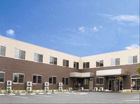 青色の空の下に建っている、室外機が設置されている様子がわかる施設外観