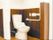 こげ茶色の壁の部分にＬ字型の手すりが設置されているトイレ個室