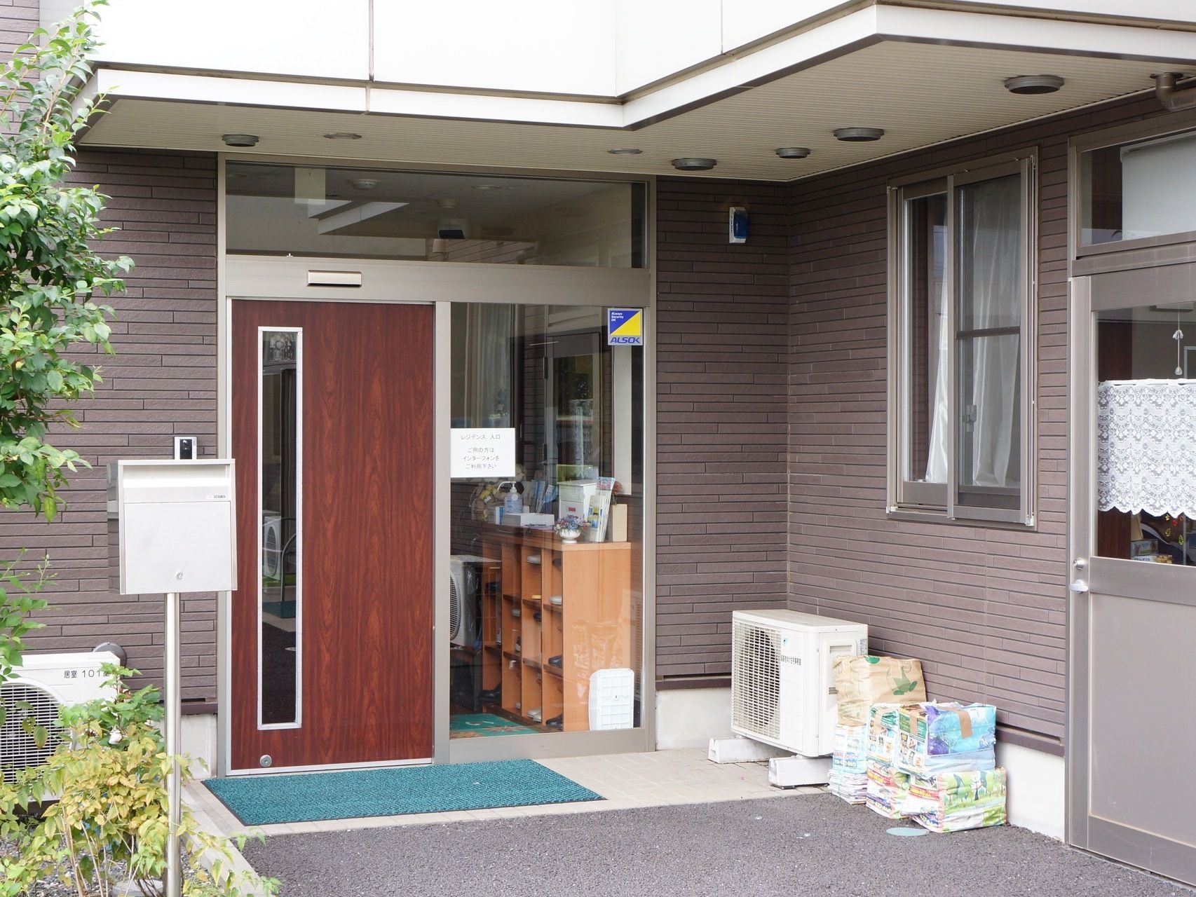 玄関は、ガラス張りになっている部分から室内の下駄箱が見える。自動ドアの部分は木が使われ、一部がガラスとなっておりデザイン性がある。