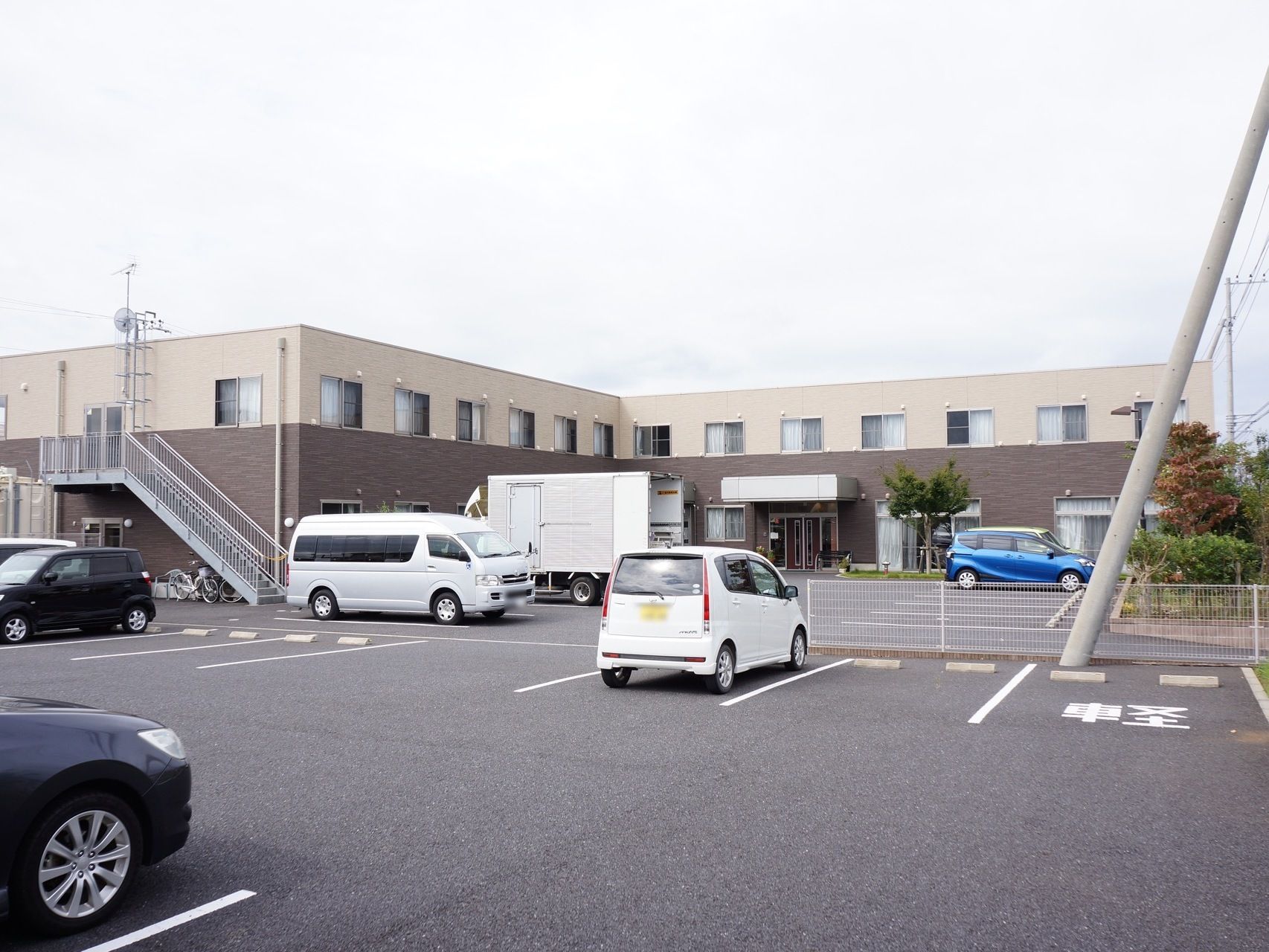 施設は、２階建ての鉄骨造りで、１階部分は茶色、２階部分はベージュ色のツートンカラーである。駐車場が広く、10台以上駐車可能である。