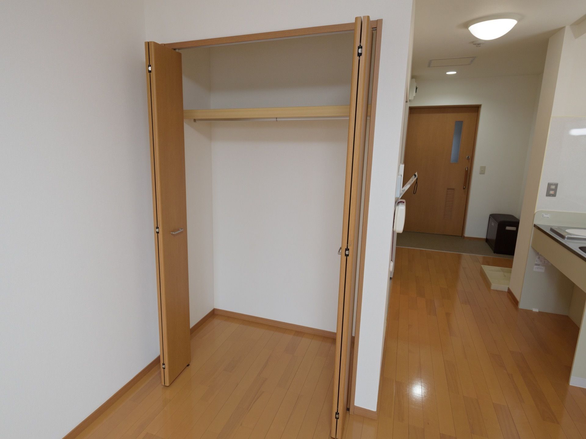 居室内のキッチンの向かいにはバリアフリーのクローゼットが完備されている。棚には小物が収納でき、洋服を掛けるポールが備え付けられている。