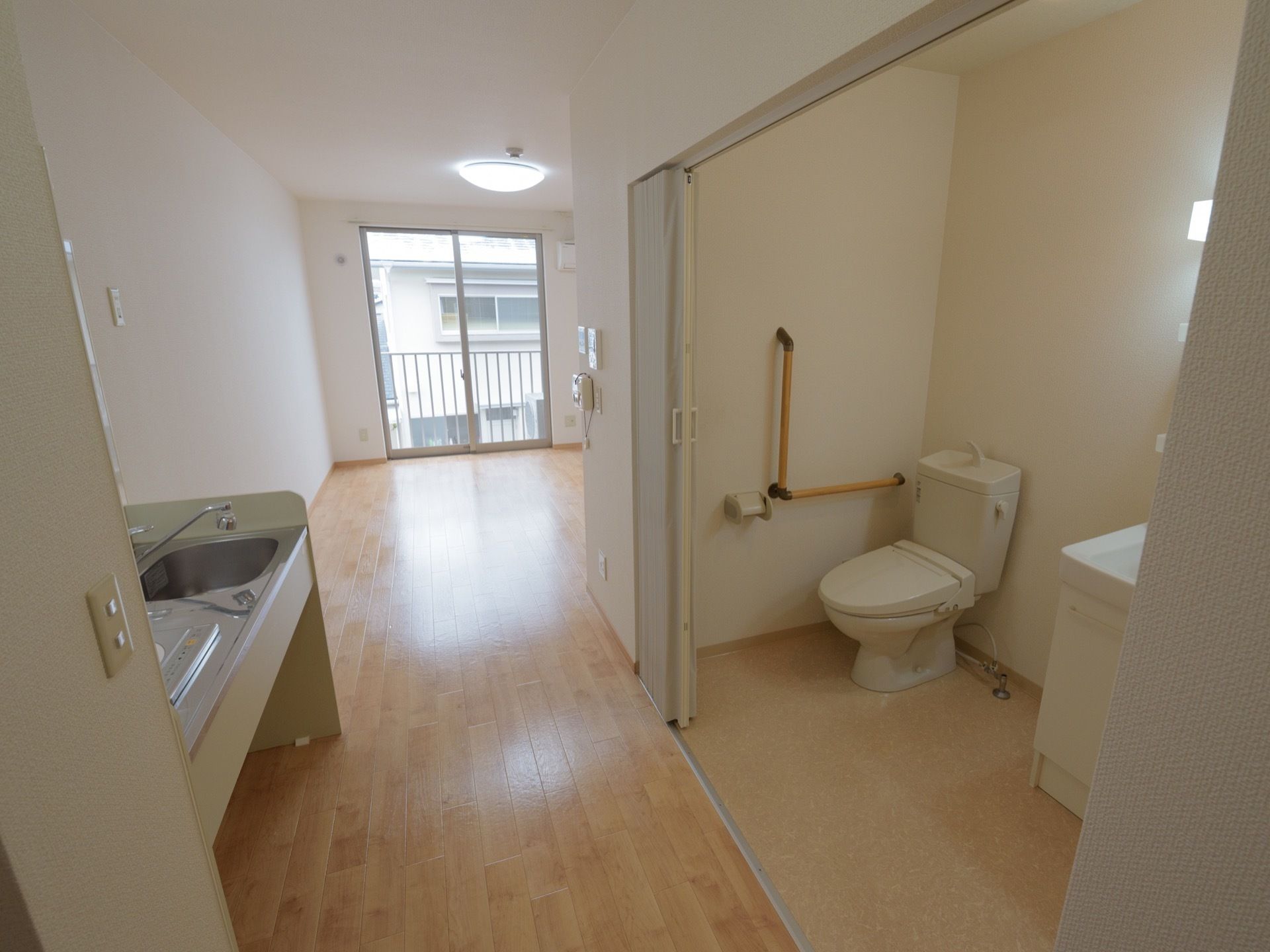 居室には出入口のそばにアコーディオンカーテンで仕切られたトイレと洗面台があり、その向かいにはキッチンの設備がある。