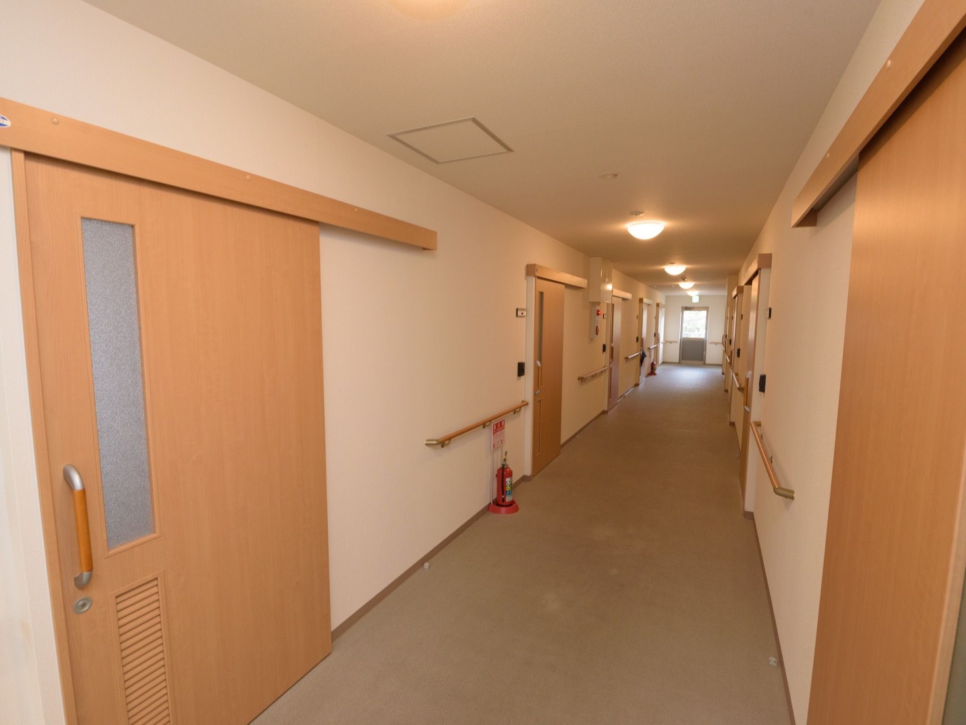 壁に手すりが設置され、消火器が置かれている。ドアは木製で、一部分が曇りガラスになっている。突当りには非常口がある。