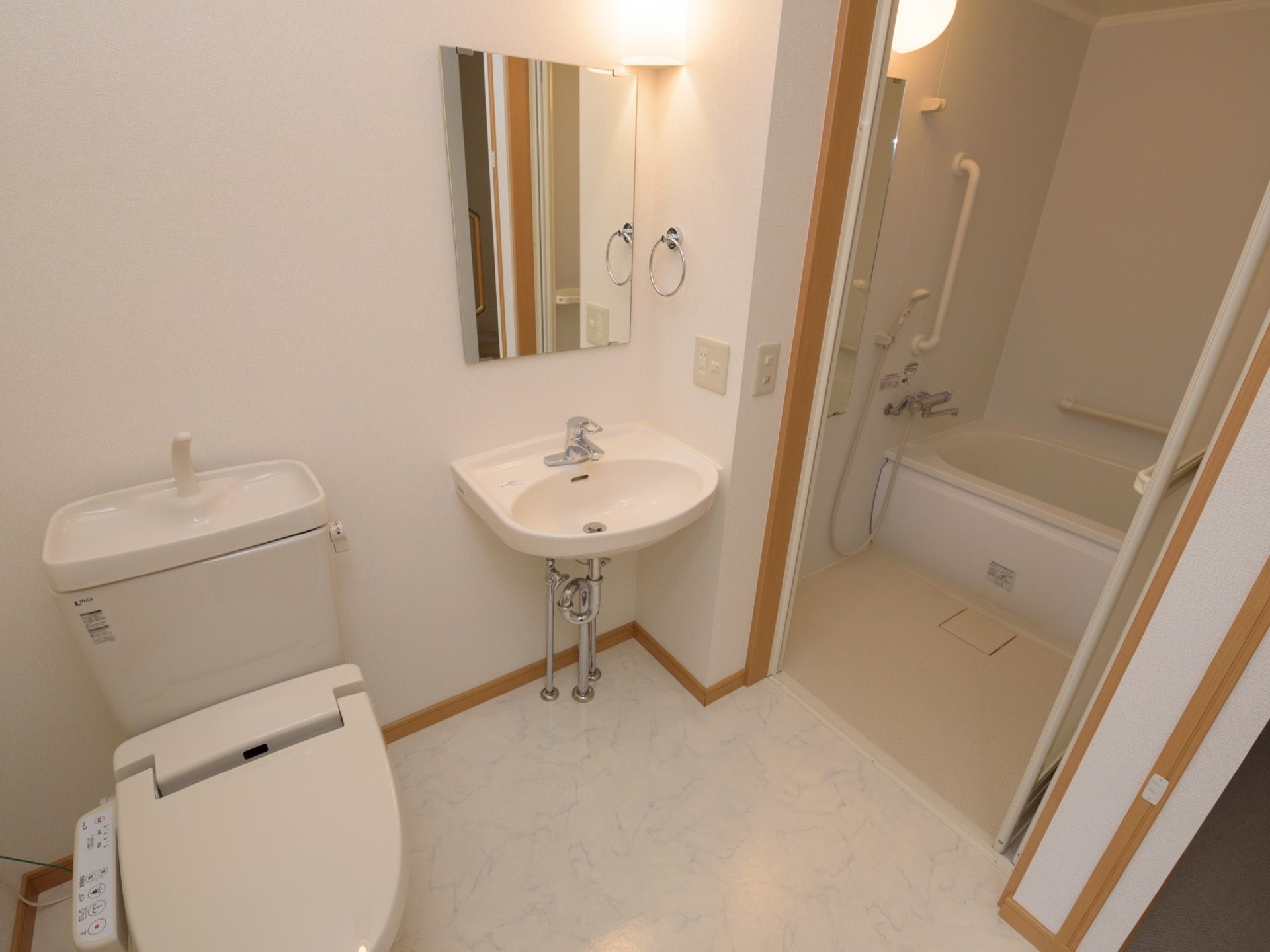 トイレと洗面台の奥にパネルドアで仕切られた浴室がある。浴室内には手すりがついていて、浴槽も低めに設置されている。