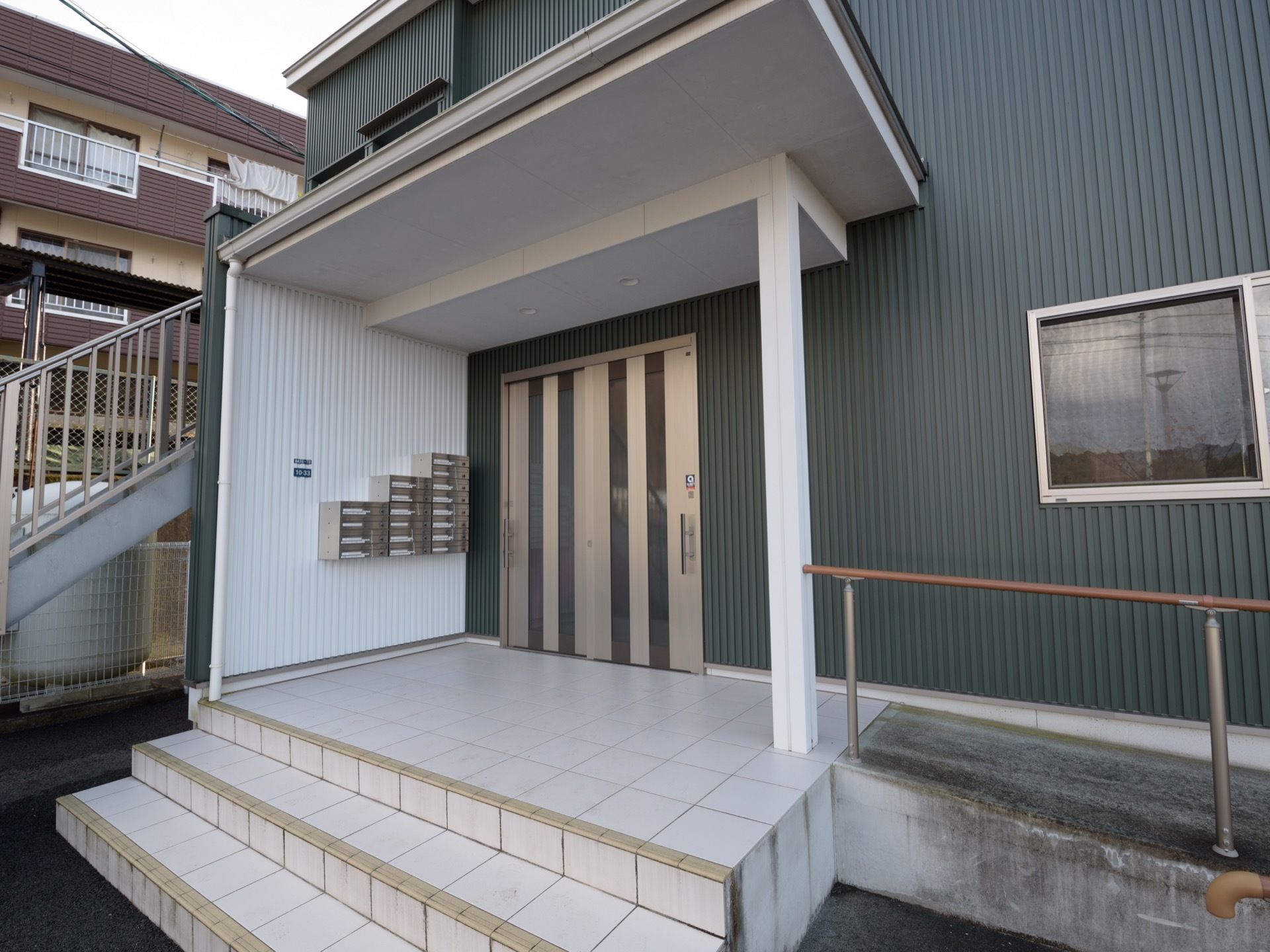 大きな庇の広い玄関ポーチがある。玄関の扉は引き違い戸で開けやすい。手すりのあるスロープがあり車椅子でも安全に移動できる。