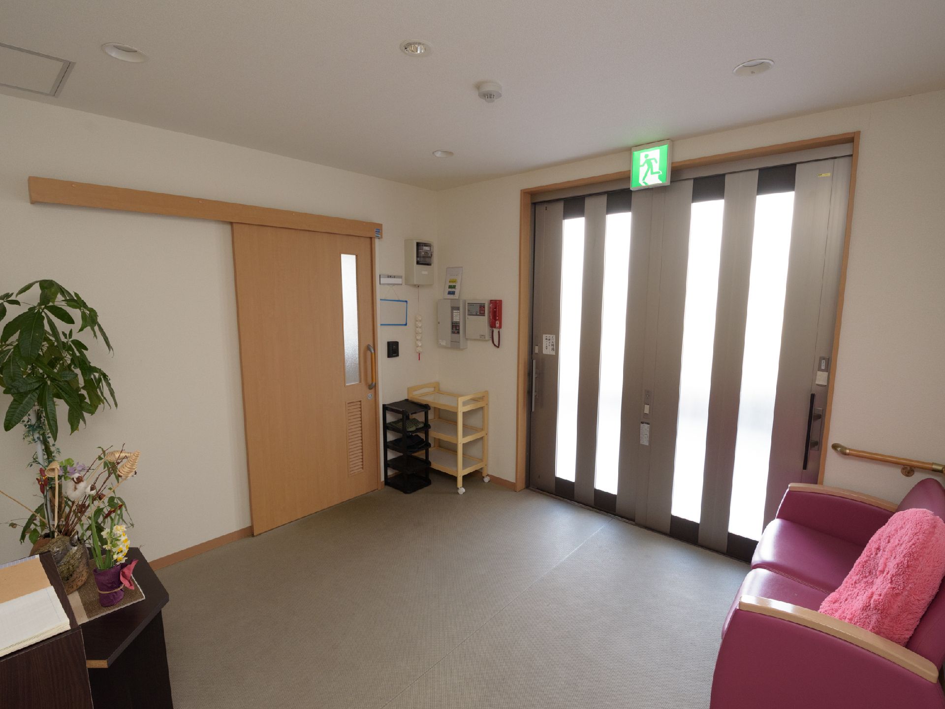 スライド式の玄関を入ってすぐの場所にピンク色のソファーが設置されている玄関ホール