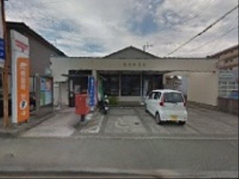 道路から入口まではスロープになっていて、途中にポストがある。敷地内に駐車場があり、入口の上にはひさしが掛かっている。