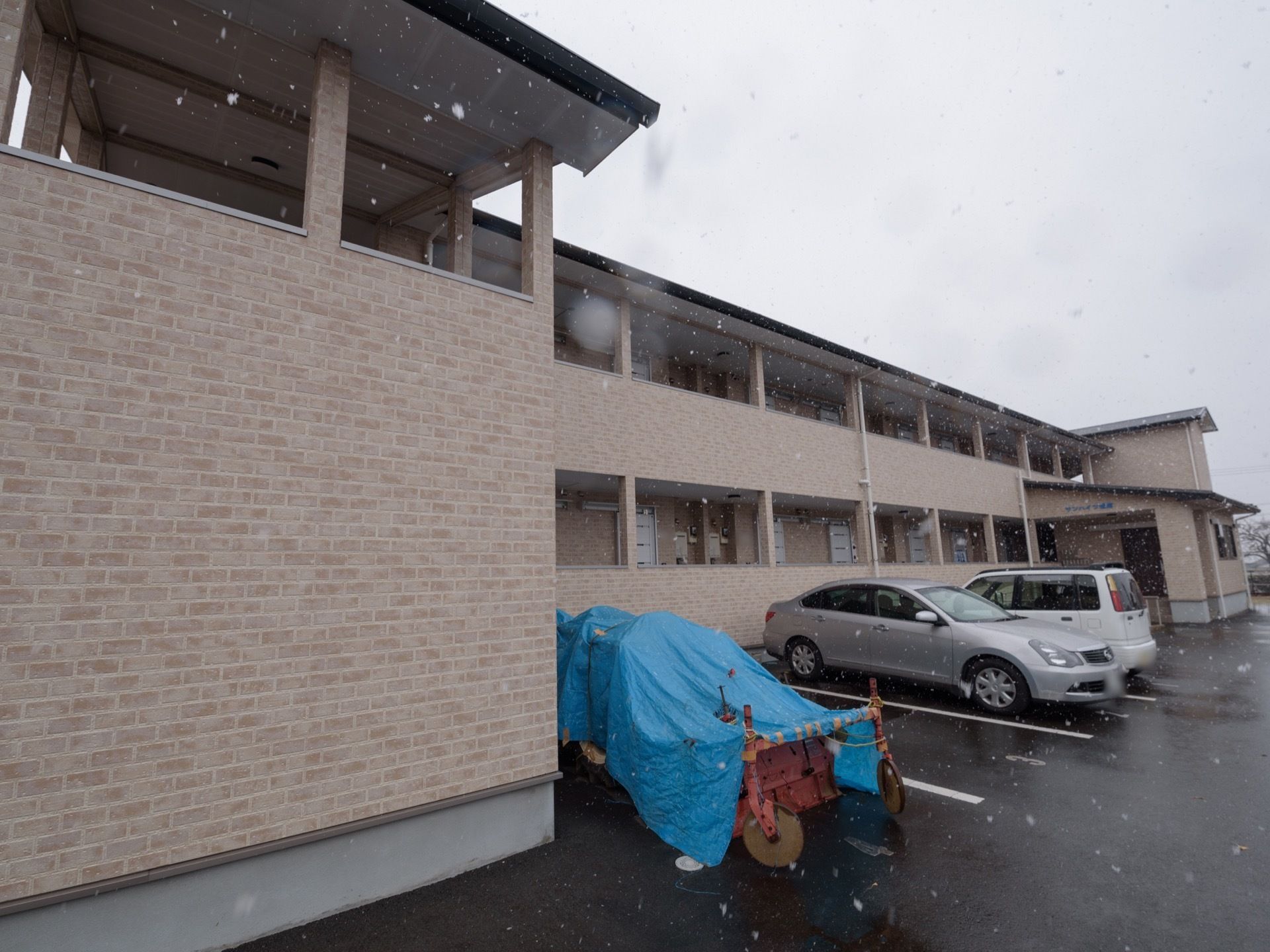 ２階建ての施設建物の前には、来訪者様用の駐車場が完備されている。駐車場の横には屋根付きの施設玄関がある。