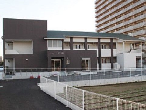 手前に畑が広がっていて、柵の向こうに建っている施設