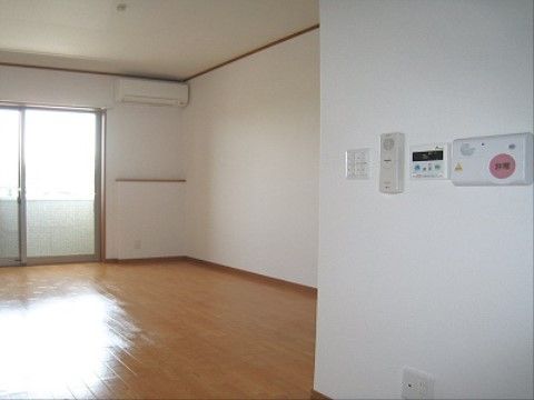 壁になースコールなどがついている居室。ベランダのガラス戸から陽の光が差し込んで、フローリングの床を明るく照らしている。