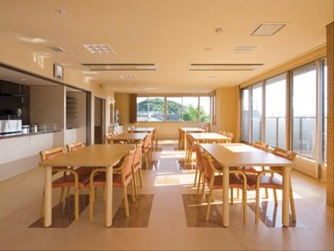 縦長の部屋の厨房の正面にはテーブルが２列に並んだ先に、前面にベランダへと続く地窓がある。横にも窓のある開放的な部屋である。