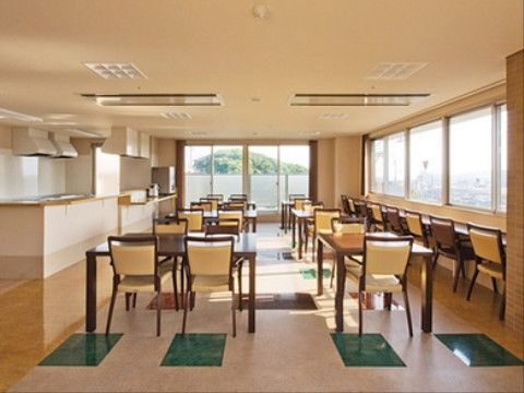明るい食堂に、椅子と机が並ぶ。見晴らしの良い景色が見ることができるカウンター席もある。奥には入居者様が利用可能な広々としたキッチンがある。