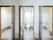 淡いベージュ色のフローリングに白い壁に手すりがついた明るいトイレが３つ並んでいる。真ん中のトイレには窓が見える。