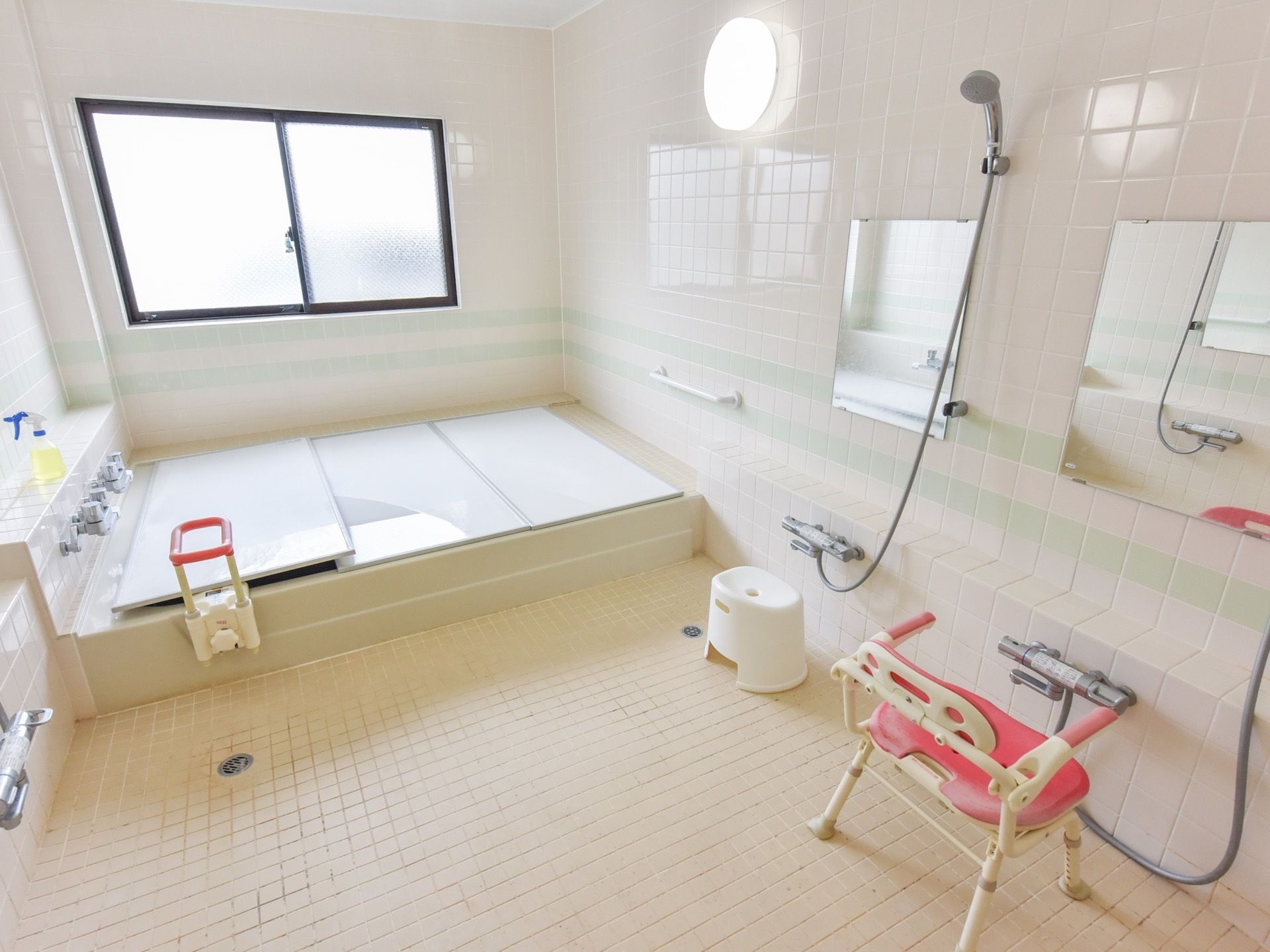 浴室は広々としており、複数で入ることができる。洗い場の鏡の前には介護用シャワーチェアーが置かれている。