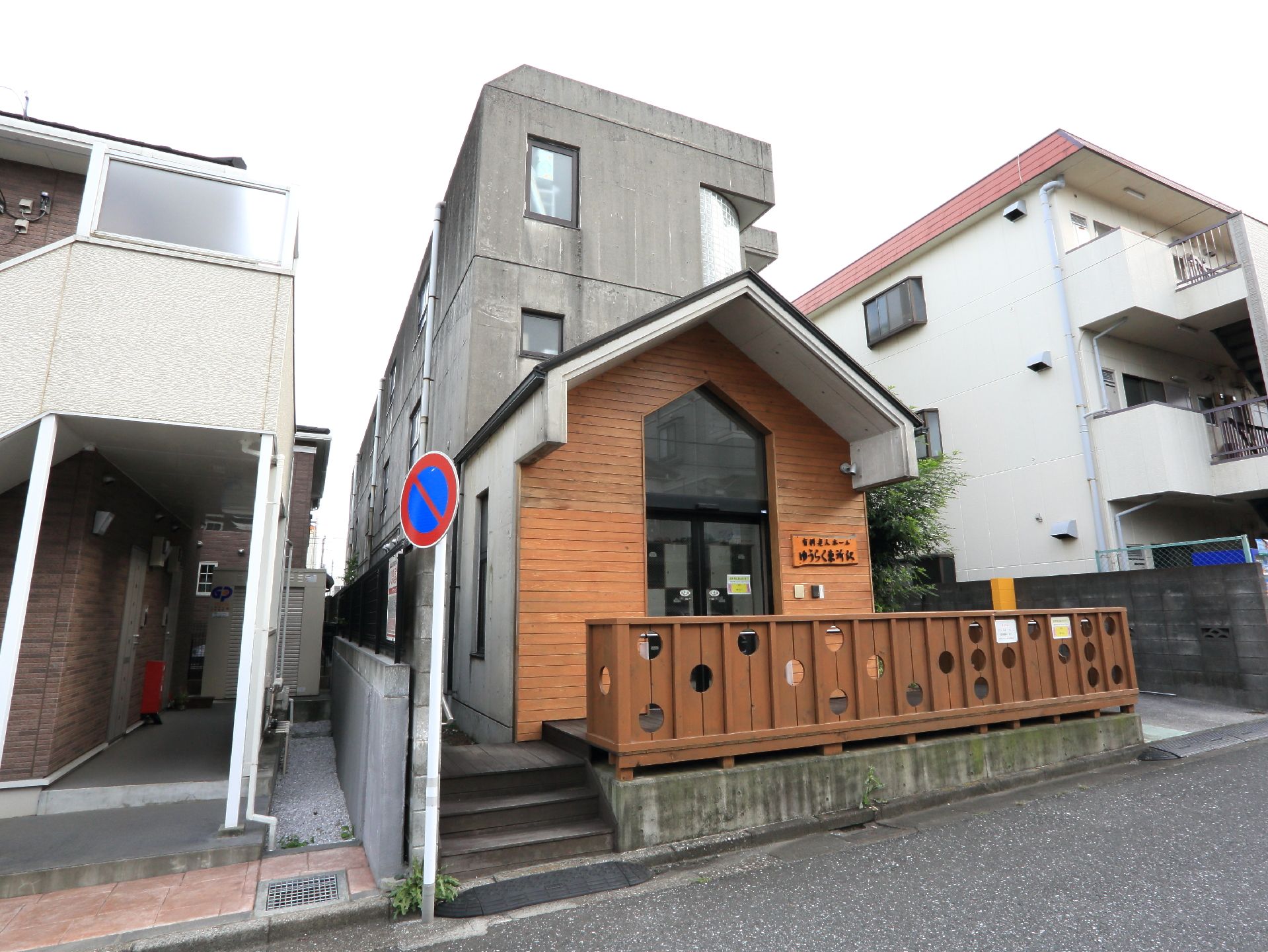 道路から見た施設の外観。建物自体は打ちっぱなしのコンクリートだが、エントランスは温かみを重視した木の材質。