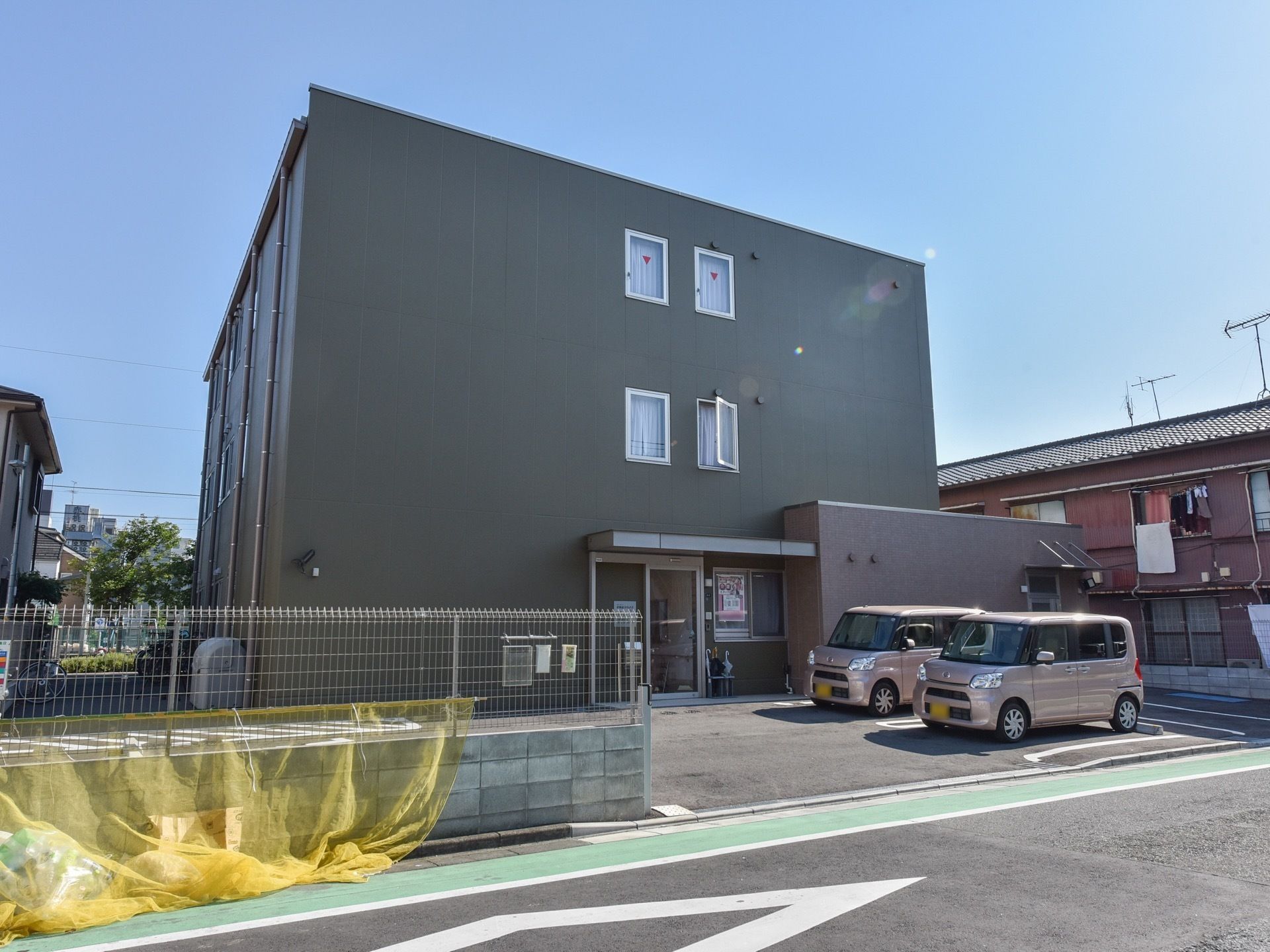 ブルーシルバーのシックな雰囲気の外壁だ。窓が真ん中に寄って設置してある。広々とした駐車スペースがある。