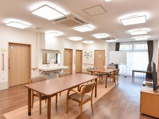 木製のダイニングテーブルセットが複数置かれたリビングダイニング。車いす対応の洗面所もある。