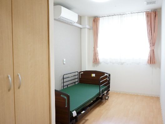 フローリングの部屋には介護ベッドやクローゼットがあり、壁には呼び出しボタンが付いている。