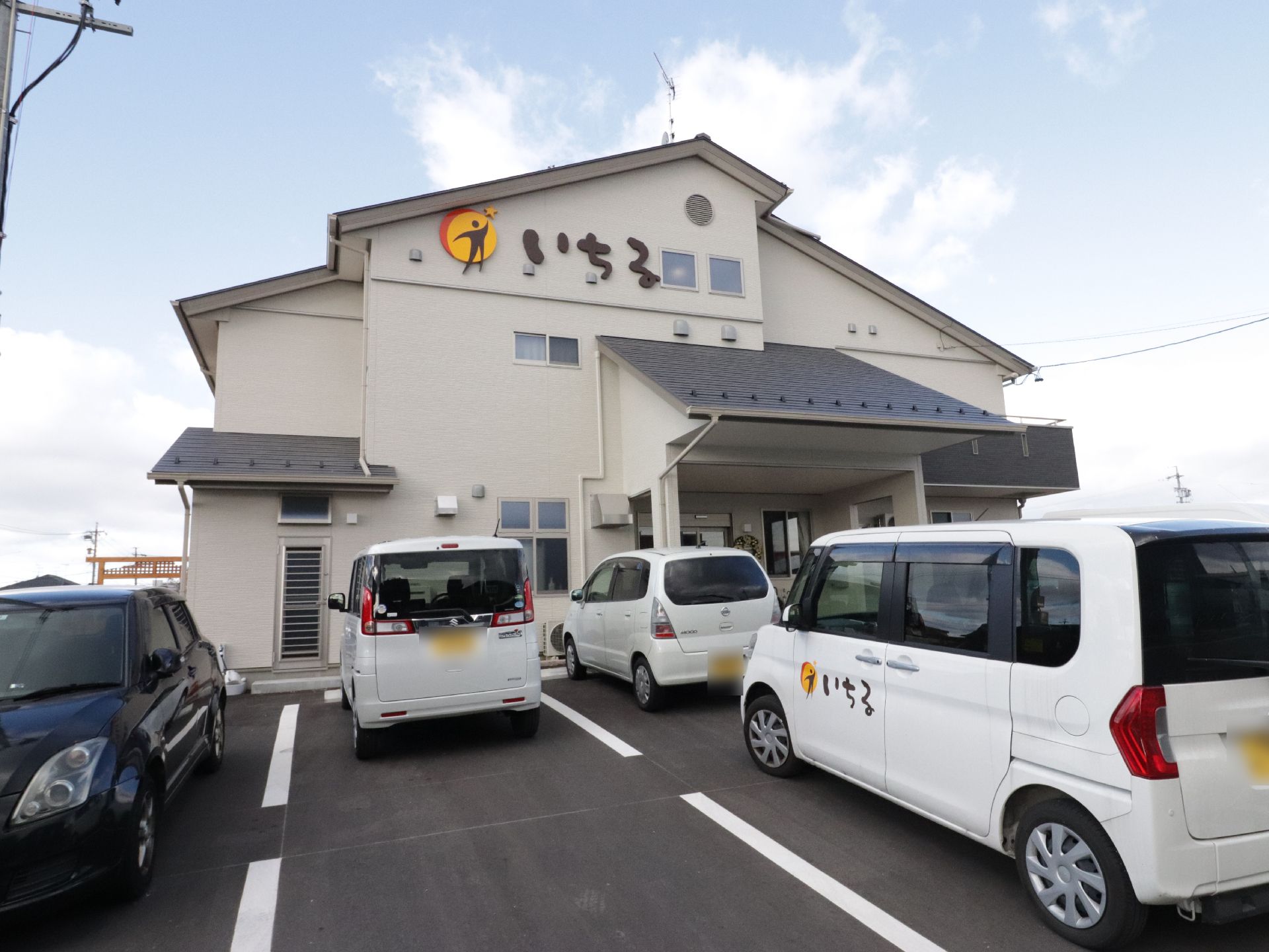 施設のロゴが印象的な建物の外観。住宅地の中にあるが、周囲に建物が立てこんでいないので、静かで落ち着いている。
