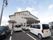 薄いグレイ色の外観の木造２階建ての施設である。建物の前方に、駐車場を設け、建物の上部の外壁には、施設名とロゴを施している。