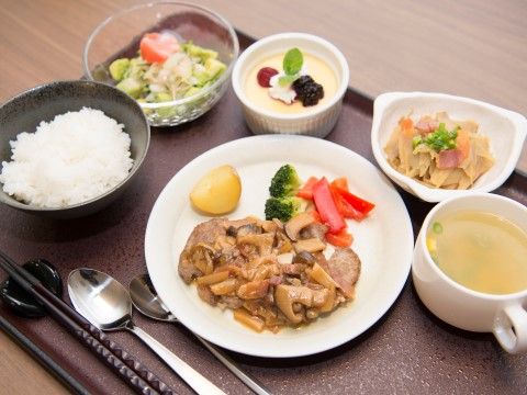 ご飯、スープ、メインのおかずのほか、野菜や付け合わせの付いた品数豊富な食事である。デザートも添えられている。