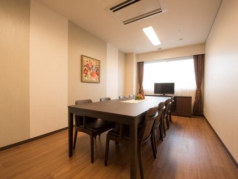 ダークブラウンの家具と同系色でまとめられた内装の、落ち着いた印象の部屋である。窓際にはテレビが置かれている。