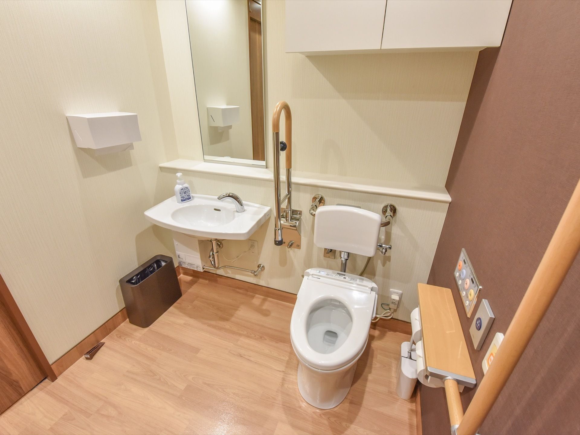 トイレには、フタのついていない便座があり、温水洗浄便座用の操作ボタンや手すりが壁際に設置されている。