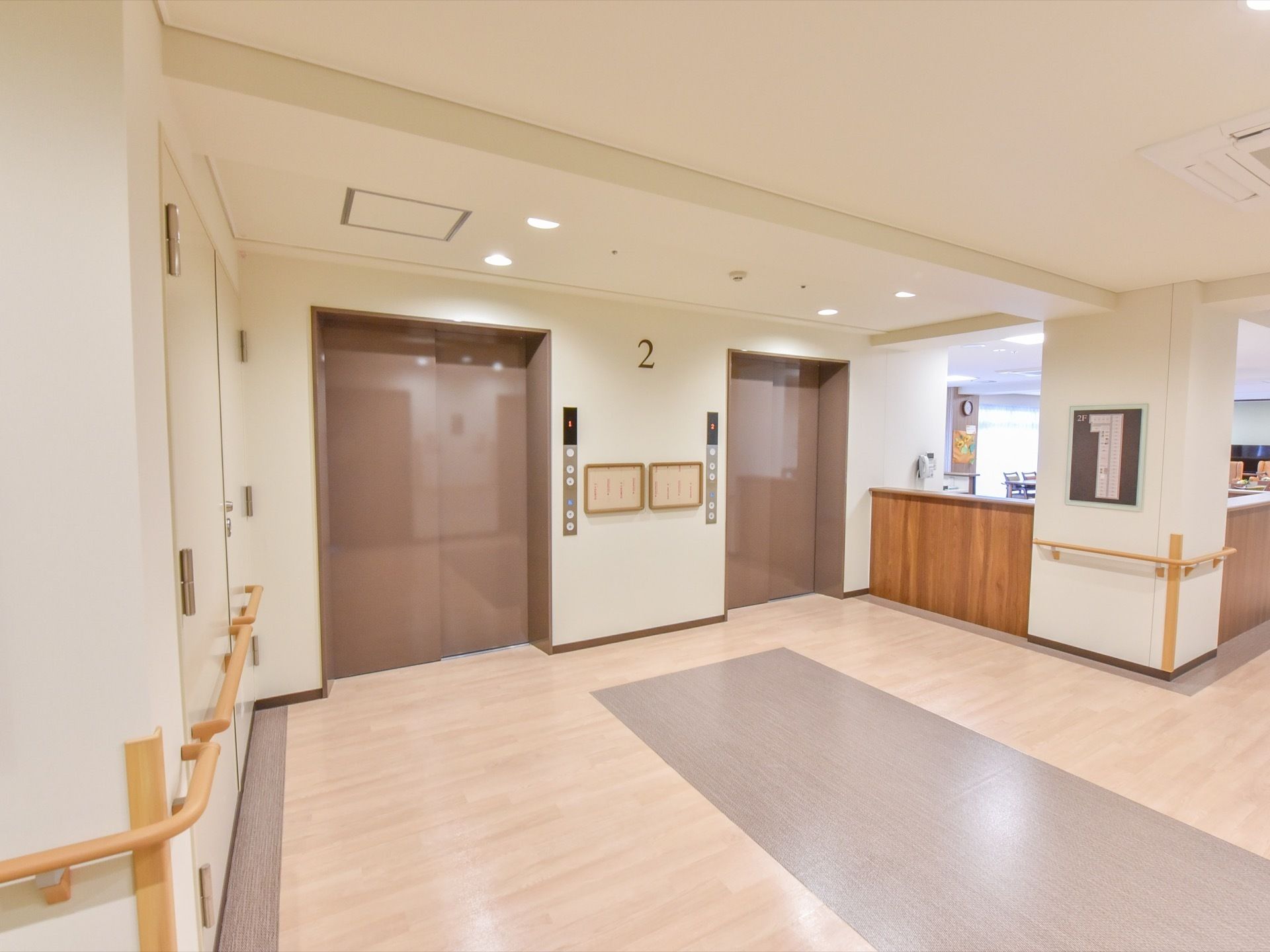２階部分のエレベーターエリアが写っており、扉は閉まった状態となっている。奥にはスペースの広い受付エリアがある。