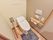 トイレにはフタが閉まった状態の便座が設置されており、マットが敷かれている。両サイドには木製の手すりが設置されている。