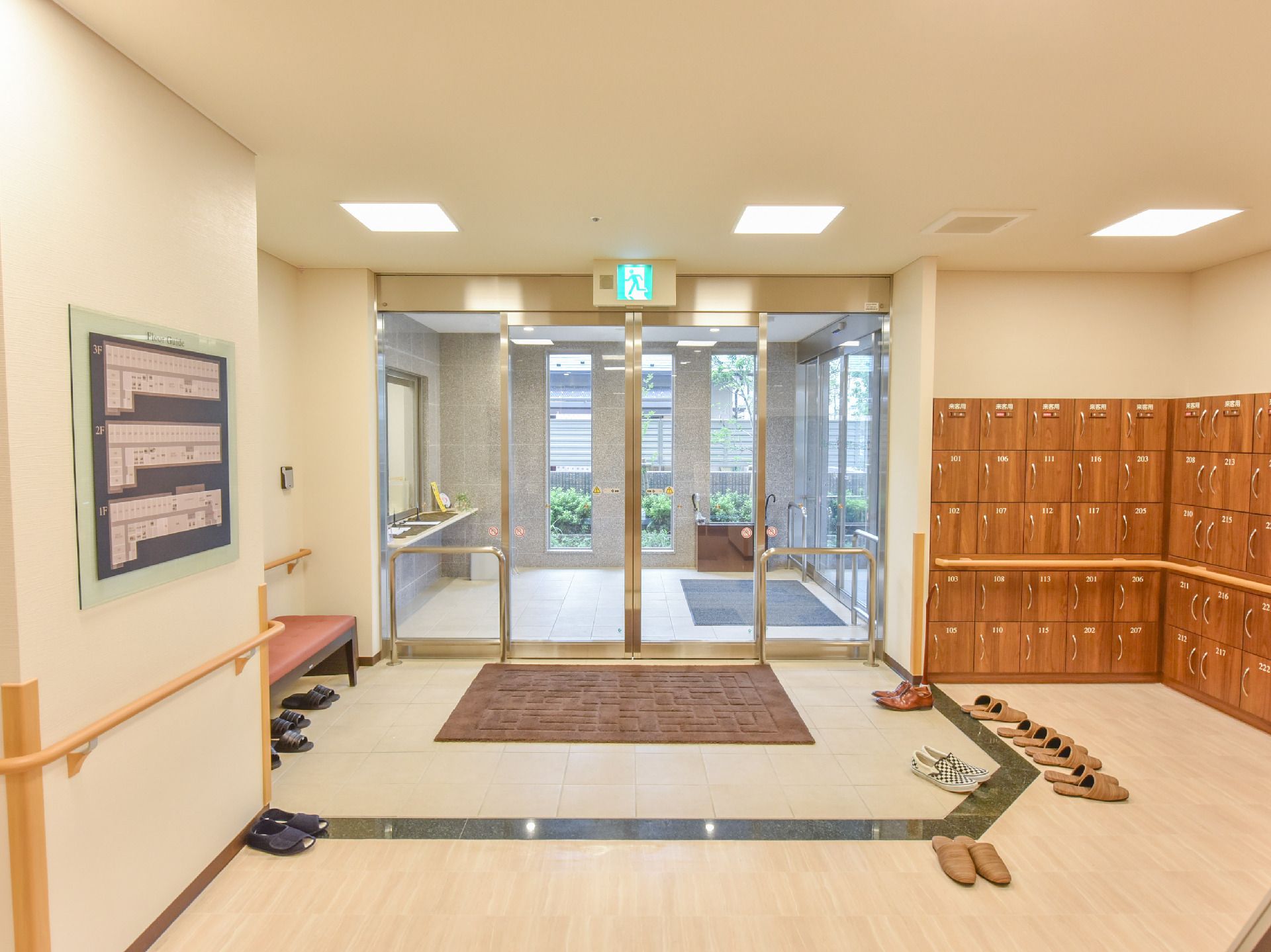 自動ドアの隣に扉付きの木製下駄箱がたくさん設置されている玄関の様子